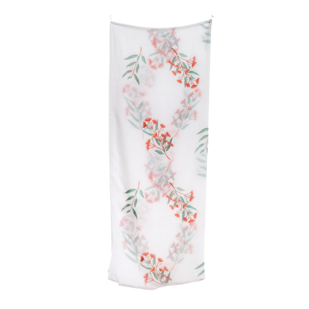 A white scarf featuring a vertical pattern of red flowers and green leaves, suspended against a plain white background.
