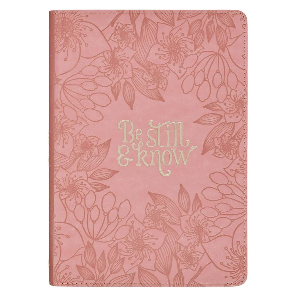 A pink journal with an embossed floral pattern and the words 'Be still & know' in a light gold metallic font on the front cover, shown against a plain white background.