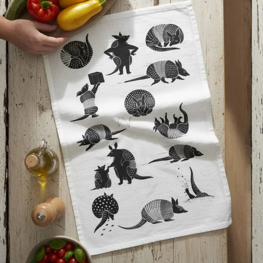 White towel with black armadillo pattern on a wooden surface with vegetables.