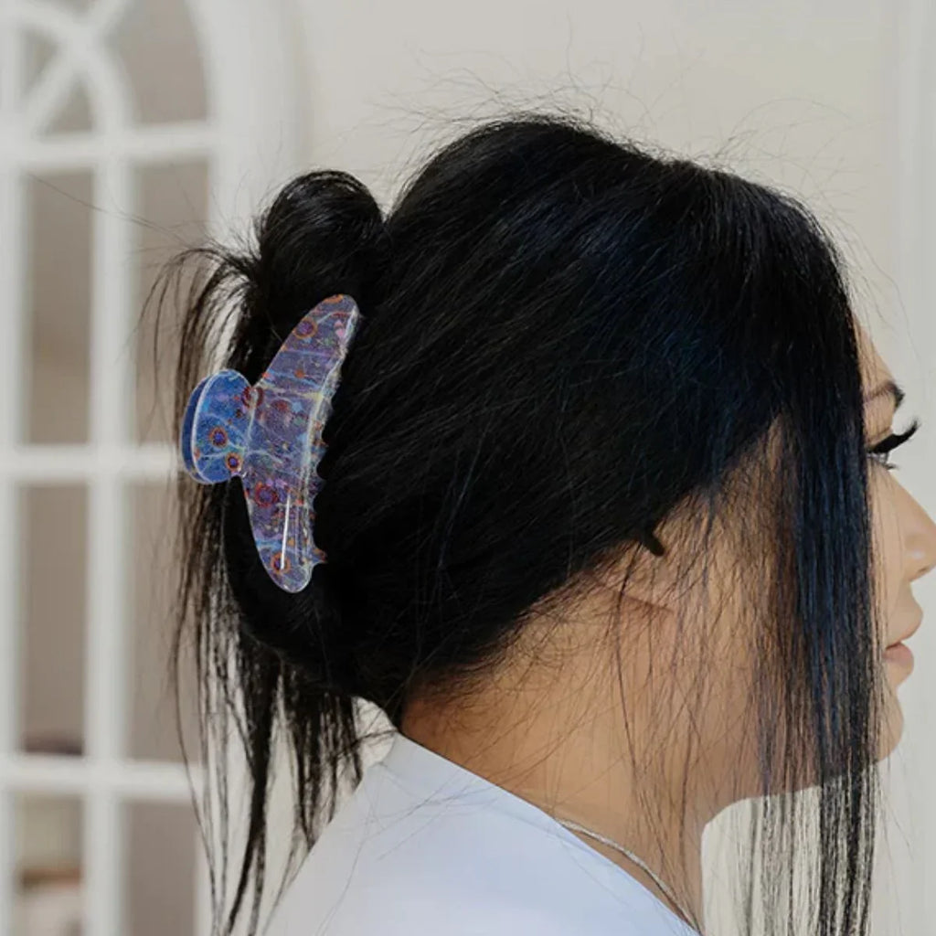 Person with a colorful butterfly hair clip in their hair against a neutral background