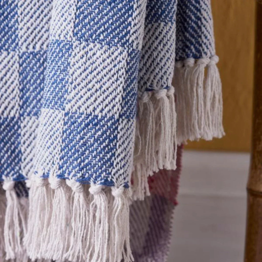 Close-up of a blue and white checkered towel with tassels on a blurred background