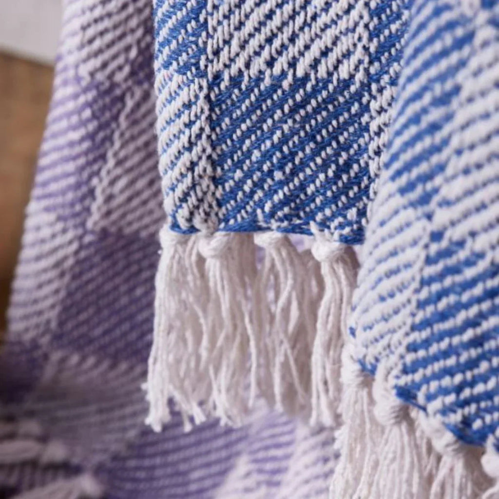 Close-up of a blue and white woven blanket with tassels