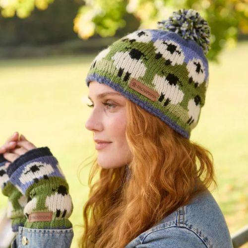 Person wearing a knitted hat and gloves with sheep pattern outdoors